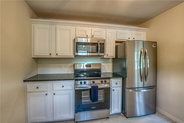 kitchen with stainless steel appliances, white cabinetry, and baseboards