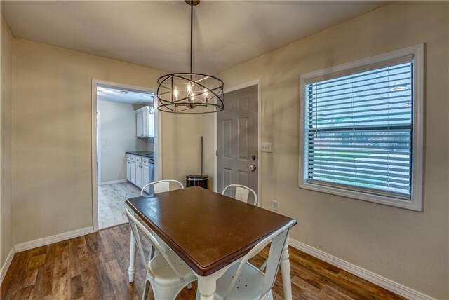 dining area featuring dark wood-type flooring, baseboards, and a chandelier