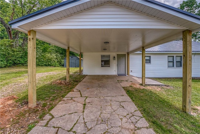view of patio / terrace featuring an outbuilding, a storage unit, driveway, and an attached carport