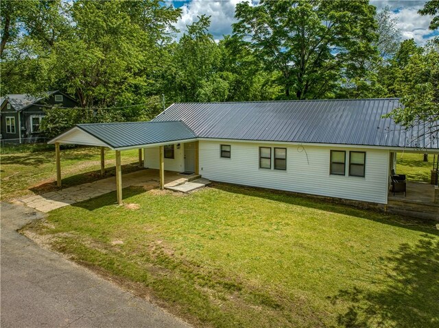 view of front of home with a front lawn, metal roof, a carport, and driveway