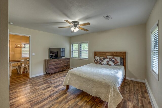 bedroom with wood finished floors, baseboards, ceiling fan, and a chandelier