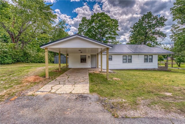 ranch-style home with a front lawn, driveway, a shed, an outdoor structure, and metal roof