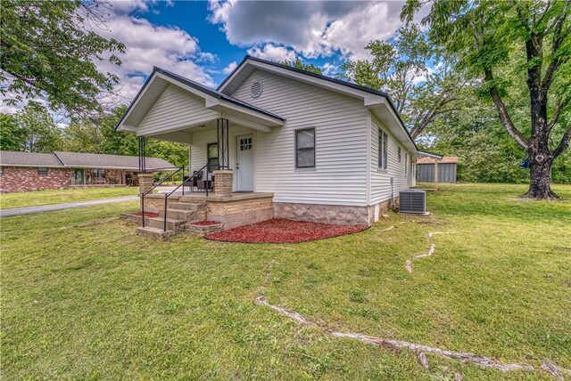 view of front facade featuring a front lawn, central air condition unit, and covered porch