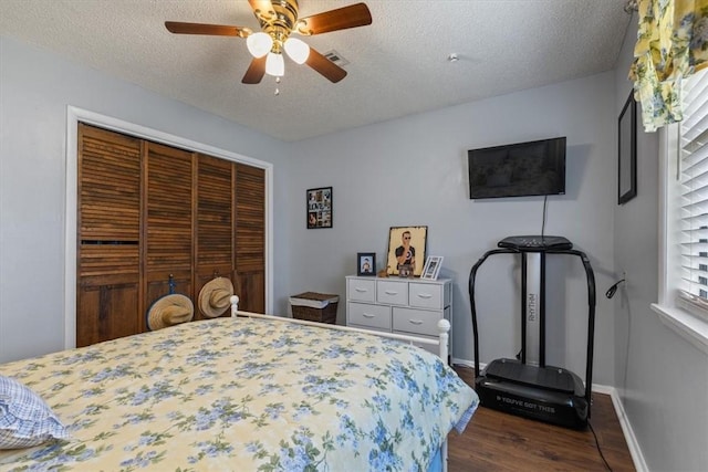bedroom with dark wood-style floors, a closet, a textured ceiling, a ceiling fan, and baseboards