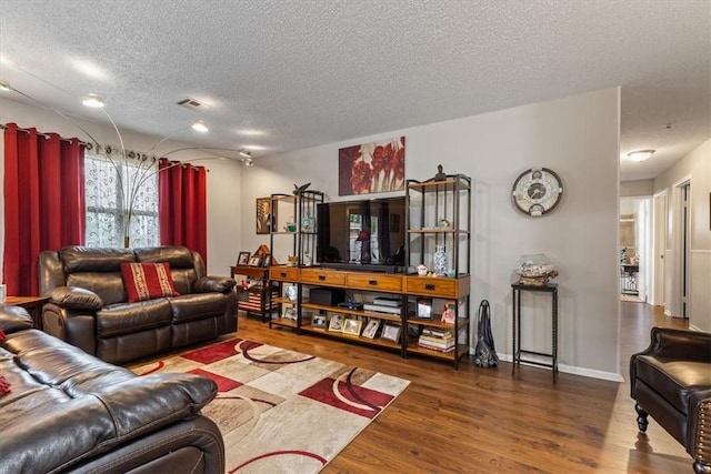 living area with a textured ceiling, wood finished floors, and baseboards