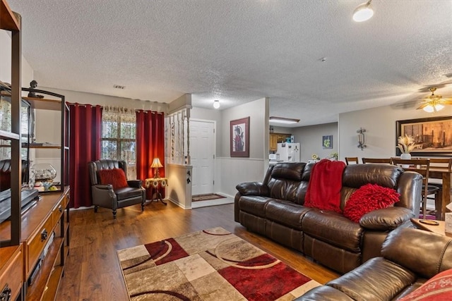 living room featuring a textured ceiling, wood finished floors, and a ceiling fan