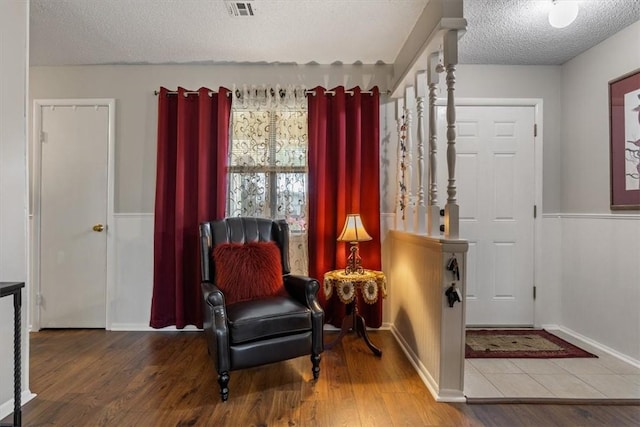 living area featuring a textured ceiling, wood finished floors, and baseboards