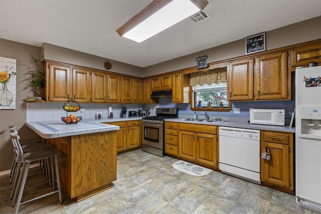 kitchen featuring white appliances, brown cabinetry, and a peninsula