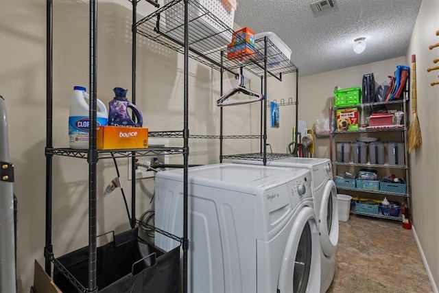 clothes washing area with separate washer and dryer, baseboards, and a textured ceiling