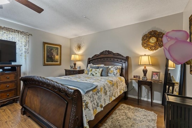 bedroom with a textured ceiling, wood finished floors, and baseboards