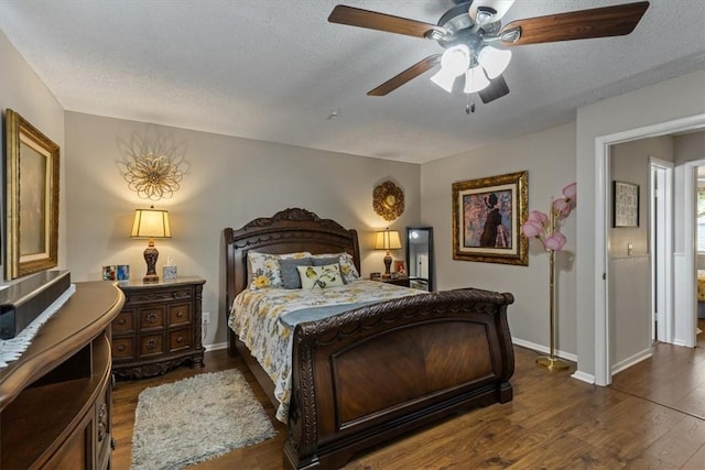 bedroom featuring dark wood-style floors, a textured ceiling, baseboards, and a ceiling fan