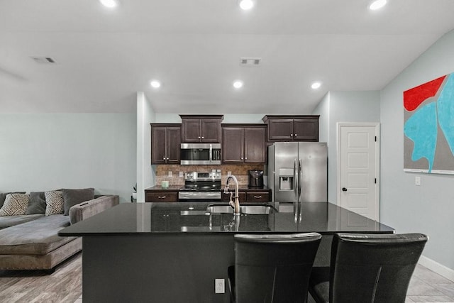 6005 Sherman St, Bentonville, AR 72713 - kitchen with appliances with stainless steel finishes, a sink, backsplash, dark brown cabinetry, and baseboards