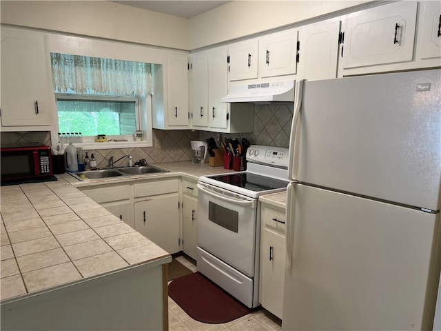 kitchen featuring white appliances, under cabinet range hood, a sink, white cabinets, and decorative backsplash