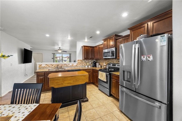 4208 SW Fieldstone Blvd, Bentonville, AR 72712 - kitchen with stainless steel appliances, tasteful backsplash, light tile patterned flooring, a peninsula, and a ceiling fan
