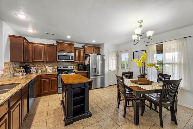 4208 SW Fieldstone Blvd, Bentonville, AR 72712 - kitchen featuring appliances with stainless steel finishes, a chandelier, tasteful backsplash, light stone counters, and hanging light fixtures