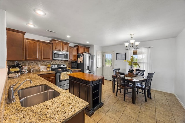 4208 SW Fieldstone Blvd, Bentonville, AR 72712 - kitchen with appliances with stainless steel finishes, a sink, a chandelier, tasteful backsplash, and light stone countertops