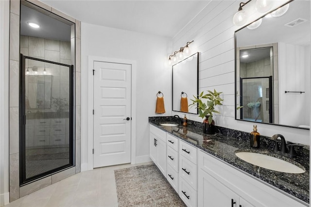 full bathroom with a stall shower, double vanity, tile patterned floors, and baseboards