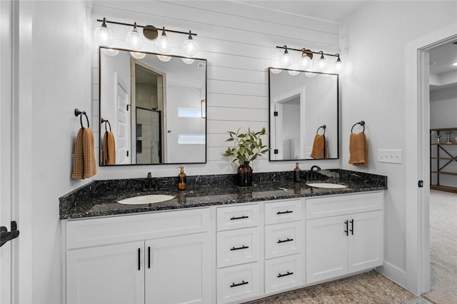 bathroom with double vanity, wood walls, and a shower with shower door