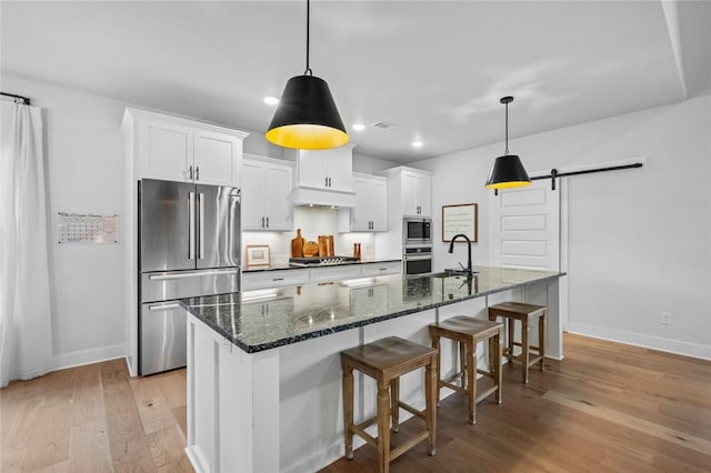 kitchen featuring appliances with stainless steel finishes, a sink, baseboards, a large island, and recessed lighting