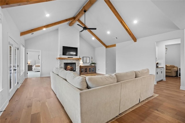 living area with light wood-type flooring, beam ceiling, a ceiling fan, a brick fireplace, and recessed lighting