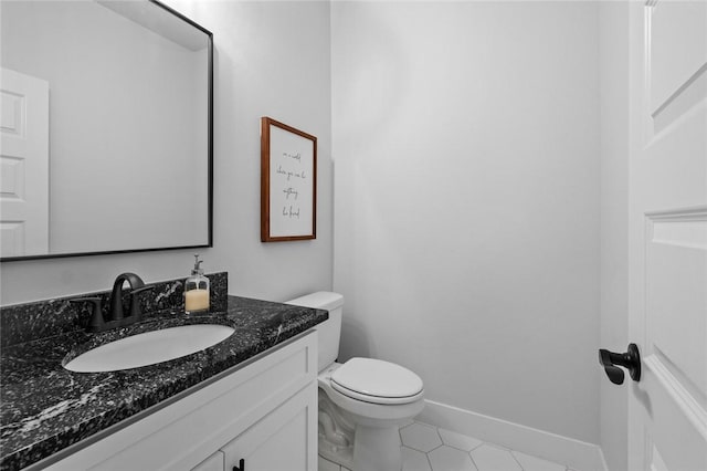 half bath featuring tile patterned floors, vanity, toilet, and baseboards