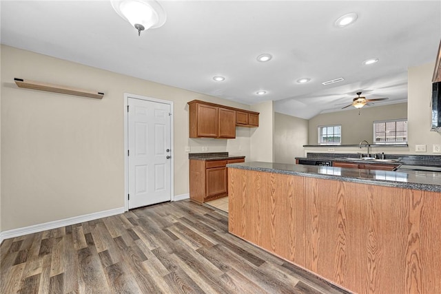 kitchen with wood finished floors, a sink, brown cabinets, recessed lighting, and a ceiling fan