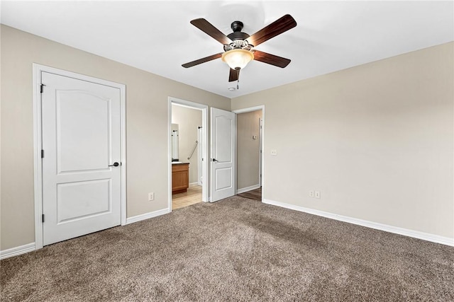 unfurnished bedroom featuring light colored carpet, baseboards, ensuite bath, and ceiling fan