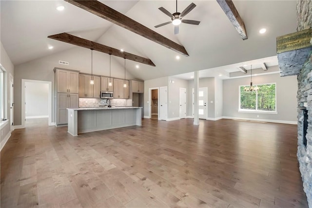 unfurnished living room with beam ceiling, ceiling fan, wood finished floors, high vaulted ceiling, and a chandelier