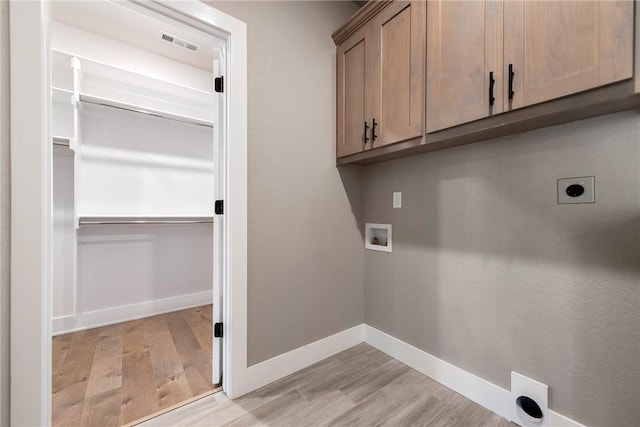 washroom featuring electric dryer hookup, hookup for a washing machine, cabinet space, and light wood-type flooring