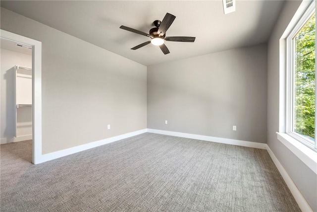 unfurnished room with healthy amount of natural light, ceiling fan, carpet flooring, and baseboards