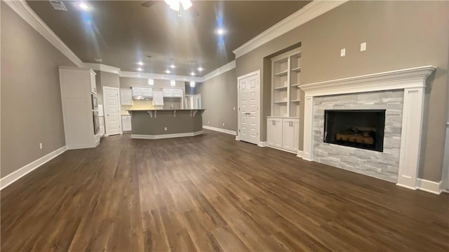 unfurnished living room featuring crown molding, a tile fireplace, dark wood finished floors, baseboards, and ceiling fan