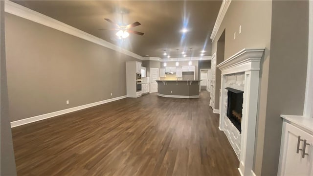 unfurnished living room featuring a ceiling fan, dark wood finished floors, a fireplace, baseboards, and crown molding