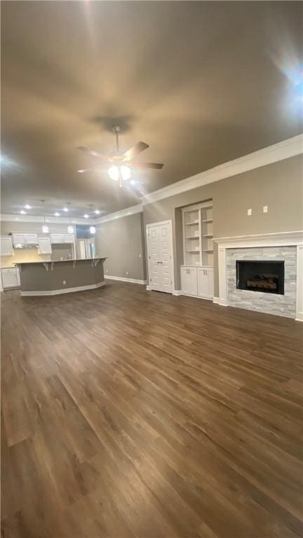 unfurnished living room featuring crown molding, ceiling fan, wood finished floors, a premium fireplace, and built in features
