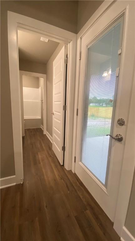 corridor with dark wood-style floors and baseboards