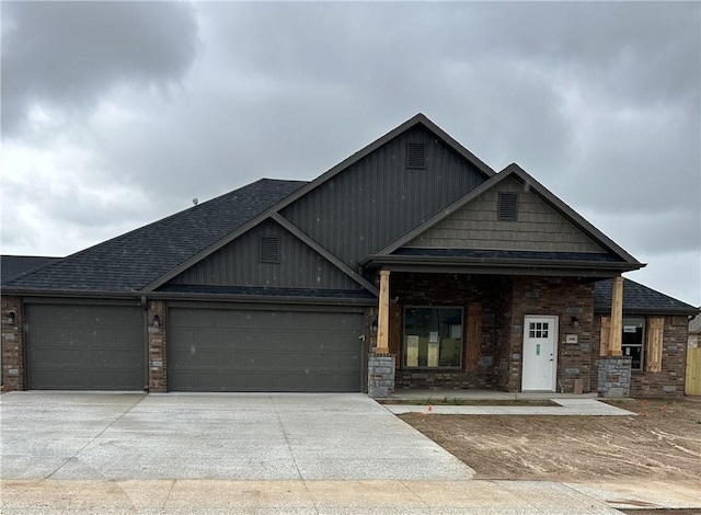 craftsman-style home featuring an attached garage, driveway, brick siding, and a shingled roof