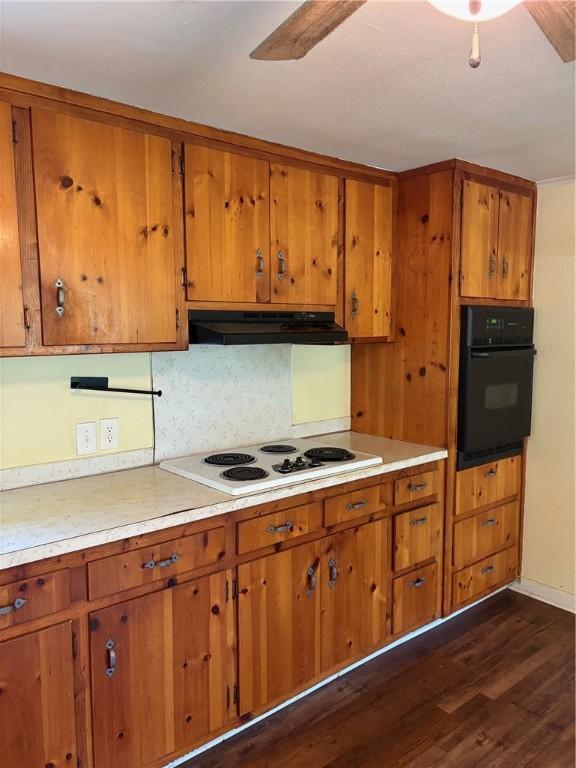 21964 Raven Rd, Elkins, AR 72727 - kitchen with black oven, brown cabinetry, white electric cooktop, under cabinet range hood, and dark wood-style flooring