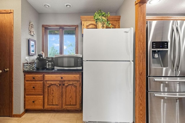 16180 Black Oak Ln, Rogers, AR 72756 - kitchen with appliances with stainless steel finishes, dark countertops, brown cabinets, and light tile patterned floors
