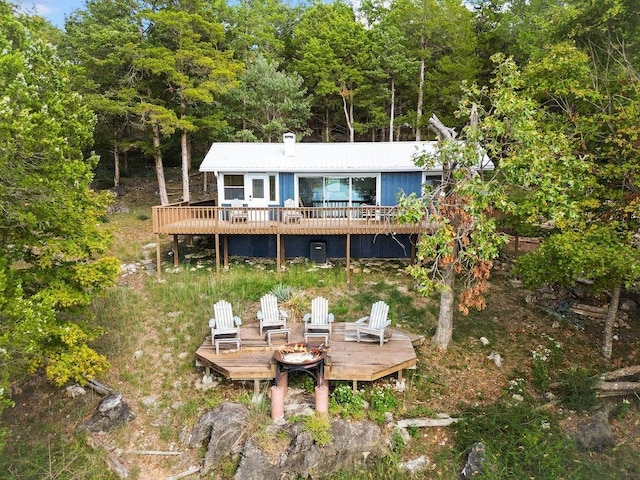 9211 Larue Rd, Rogers, AR 72756 - back of house featuring a wooden deck, an outdoor fire pit, a forest view, and a chimney