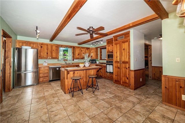 398 Northfork Dr, Berryville, AR 72616 - kitchen featuring appliances with stainless steel finishes, beam ceiling, a sink, wooden walls, and wainscoting