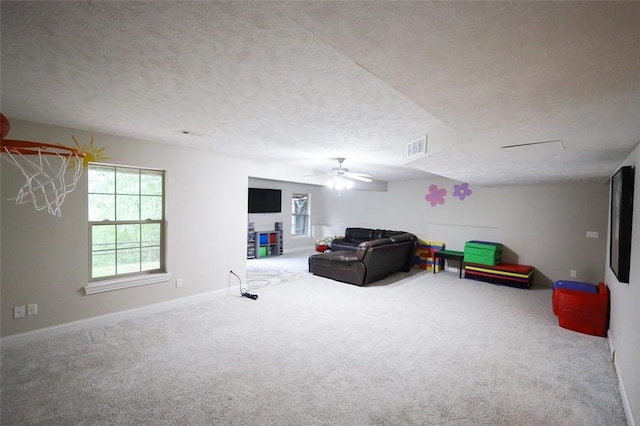 carpeted living area with plenty of natural light, a textured ceiling, ceiling fan, and baseboards