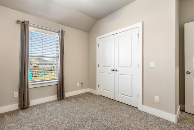 unfurnished bedroom with carpet, vaulted ceiling, a closet, and baseboards