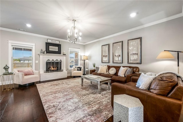 living room featuring a chandelier, dark wood-style flooring, ornamental molding, a lit fireplace, and recessed lighting