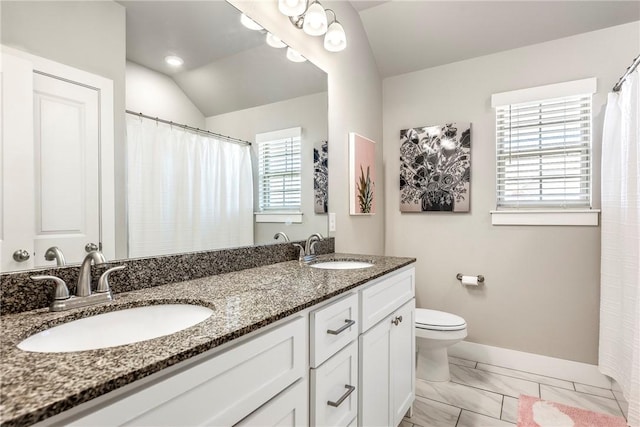 bathroom with baseboards, toilet, marble look tiles, double vanity, and vaulted ceiling