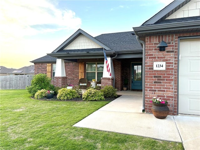 entrance to property featuring brick siding, covered porch, and roof with shingles