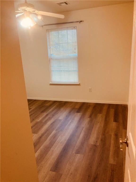 empty room featuring ceiling fan, wood finished floors, and baseboards