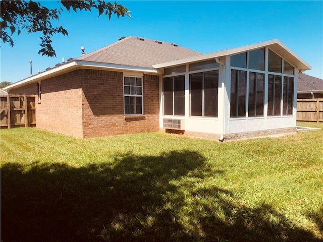 back of property featuring brick siding, a sunroom, and a shingled roof