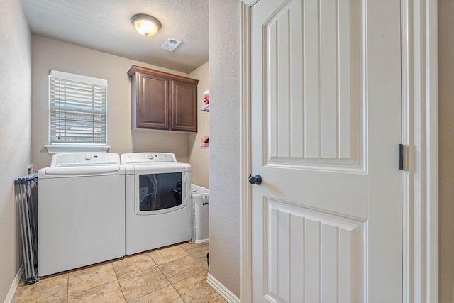 washroom with washing machine and dryer, cabinet space, and light tile patterned floors