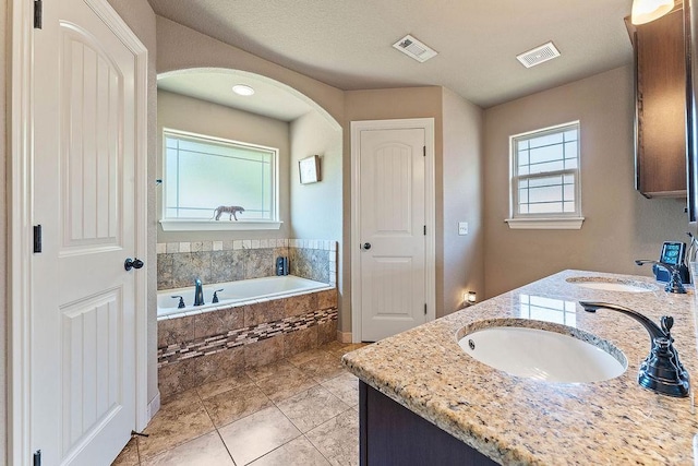 bathroom featuring a garden tub, tile patterned floors, and double vanity