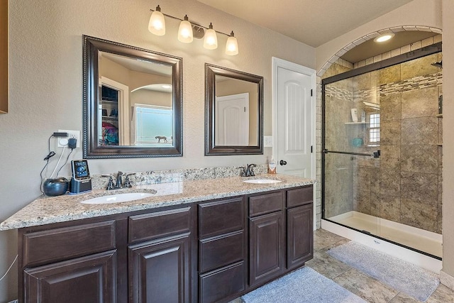 full bathroom with a shower stall and double vanity