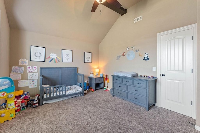 carpeted bedroom with a crib, vaulted ceiling, and ceiling fan